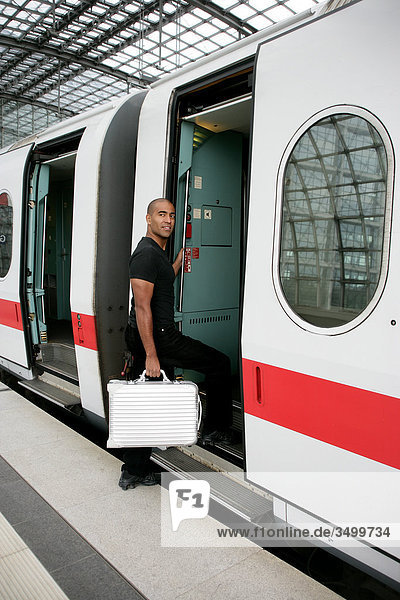 Mann mit Koffer steigt in einen Zug