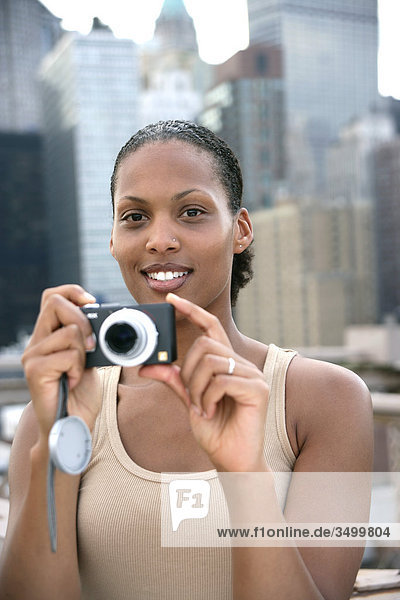 Woman holding a digital camera  skyline of New York in the background  USA