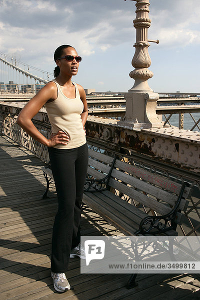 Woman standing on the Brooklyn Bridge with hands on her hips  New York City  USA