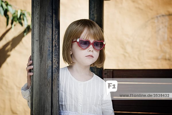 Mädchen mit herzförmigen Sonnenbrille hält Säule