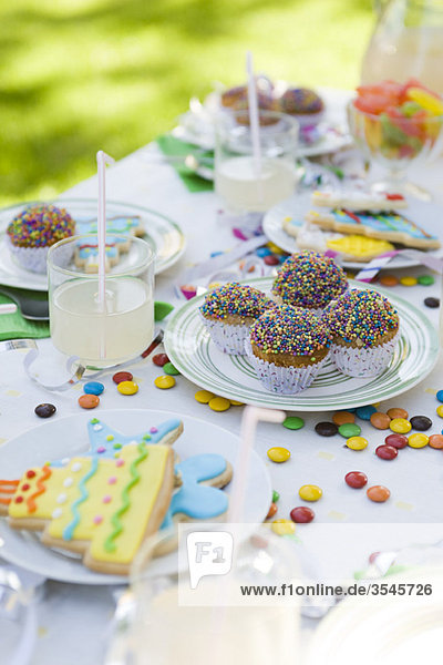 Eisgebäck und Muffins auf dem Tisch mit Streamer und Bonbons verziert