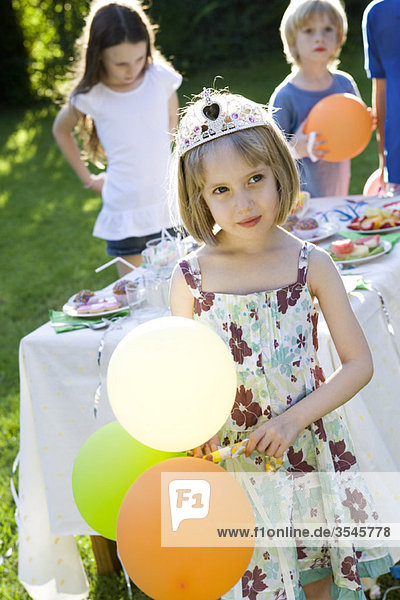 Mädchen mit Diadem und Luftballons auf der Outdoor-Party