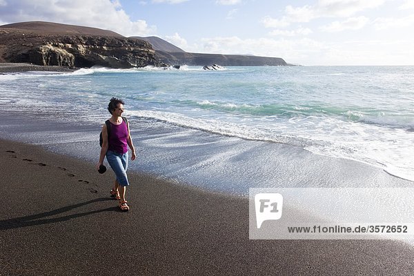 Frau geht am Strand spazieren Ajuy Fuerteventura Spanien