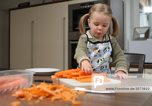 Mädchen hilft beim Karotten schälen