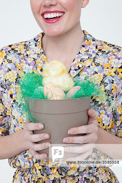 Junge Frau mit Osterküken und Eiern im Blumentopf
