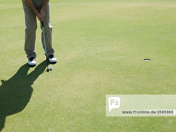 Mann spielt Golf  auf Putting Green