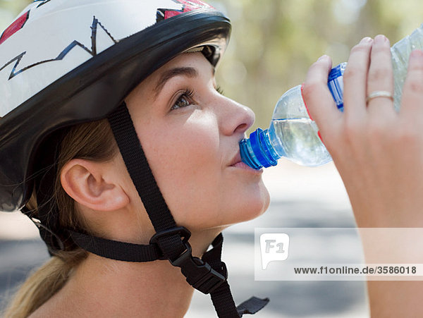 Young female cyclist drinking water