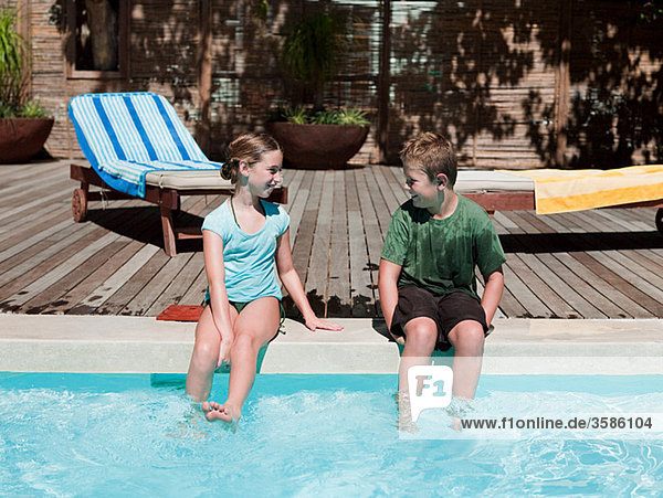 Boy and girl on edge of swimming pool