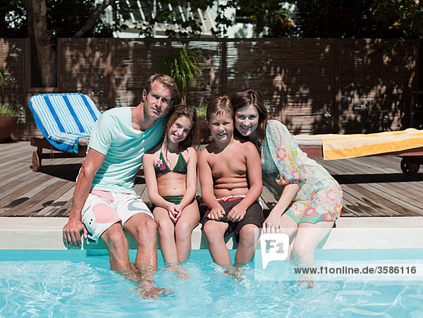 Familie sitzt am Rande des Schwimmbades