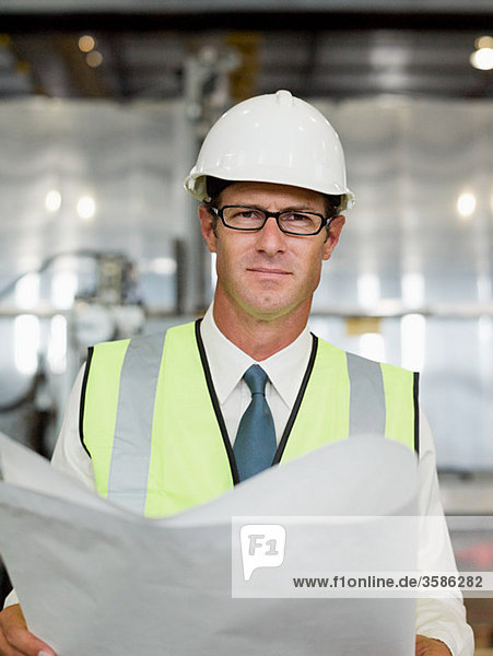 Mature man with blueprint in factory  portrait