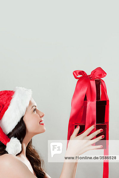 Junge brünette Frau mit Weihnachtsmütze und Weihnachtsgeschenk