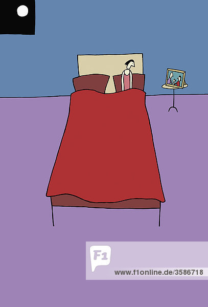Einsame Frau im Bett schaut auf Familienfoto