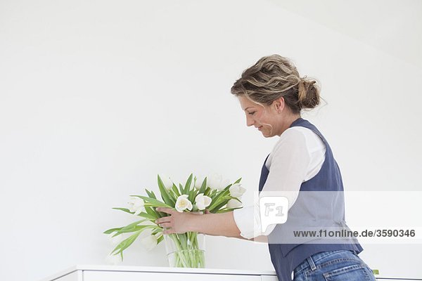 Frau stellt Tulpen in eine Vase