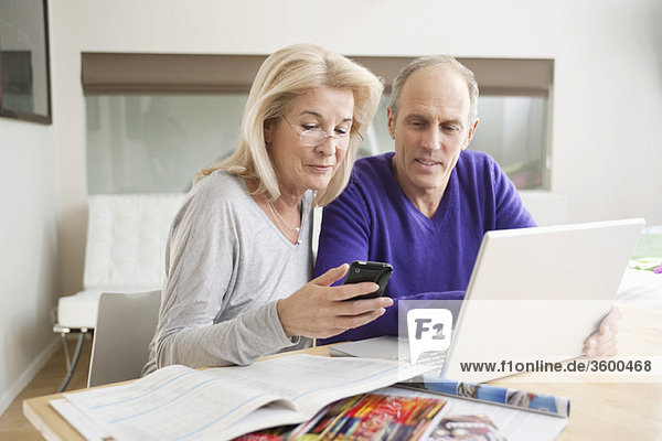Frau Textnachrichten auf einem Handy mit ihrem Mann neben ihr sitzend