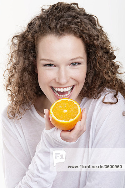 Porträt einer Frau  die eine halbe Orange hält und lacht