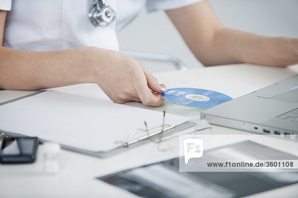 Ärztin beim Einlegen einer CD in einen Laptop