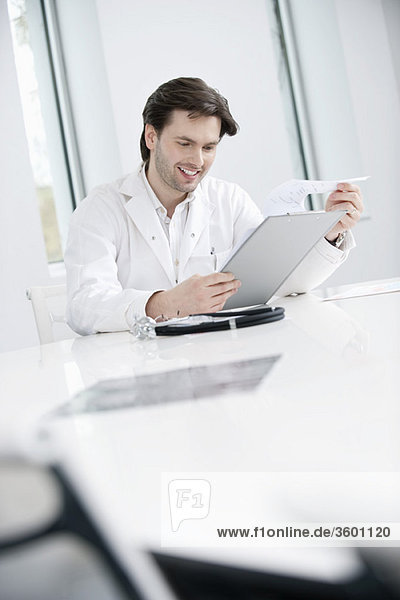 Male doctor examining a medical report and smiling