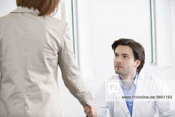 Arzt schüttelt die Hand mit einer Frau