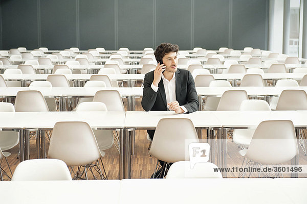 Geschäftsmann sitzt in einer Cafeteria und redet mit dem Handy