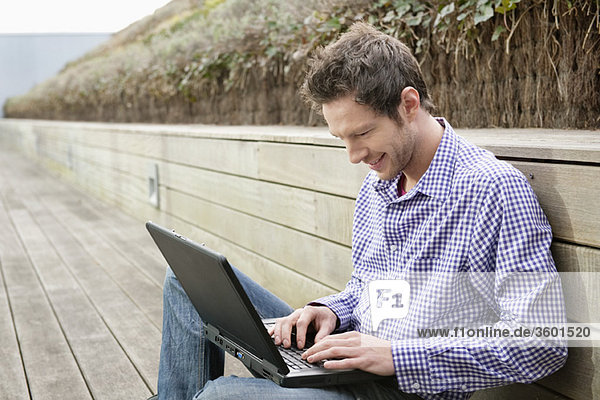 Mann mit einem Laptop auf einer Promenade
