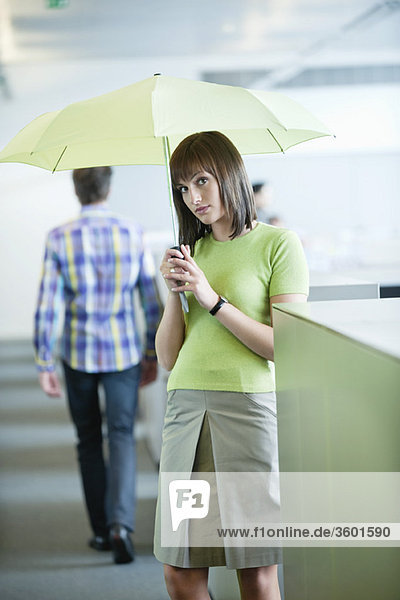 Geschäftsfrau mit Schirm im Büro