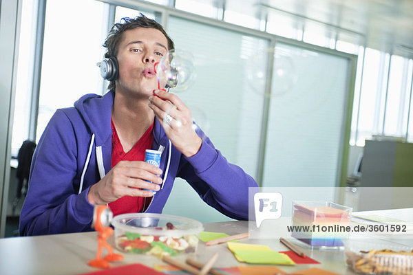 Businessman blowing bubbles in an office