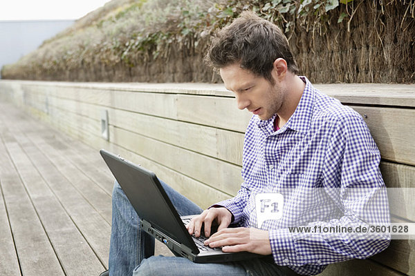 Mann mit einem Laptop auf einer Promenade