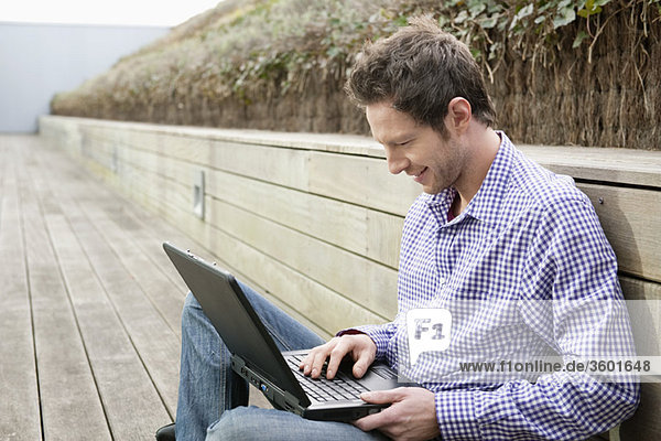 Mann mit einem Laptop auf einer Promenade
