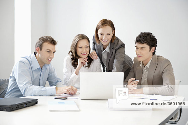 Geschäftsleute betrachten einen Laptop in einem Vorstandszimmer