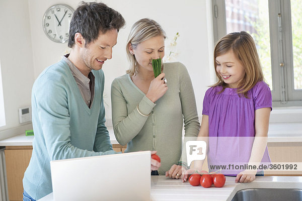 Family cooking with the recipe on a laptop