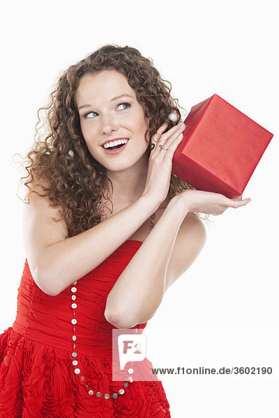 Frau hält ein Geschenk in der Nähe ihres Ohres