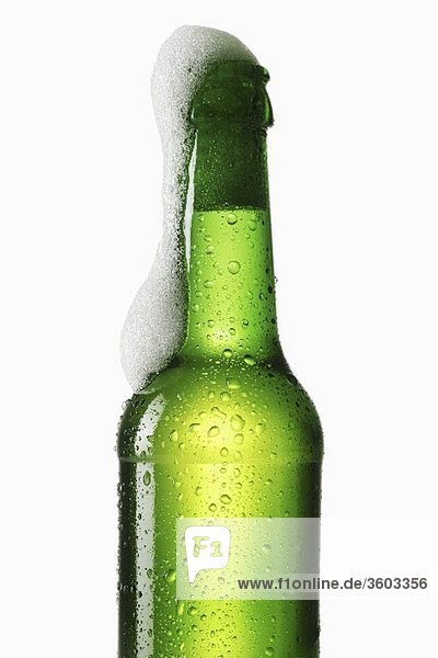 Bier schäumt aus grüner Flasche