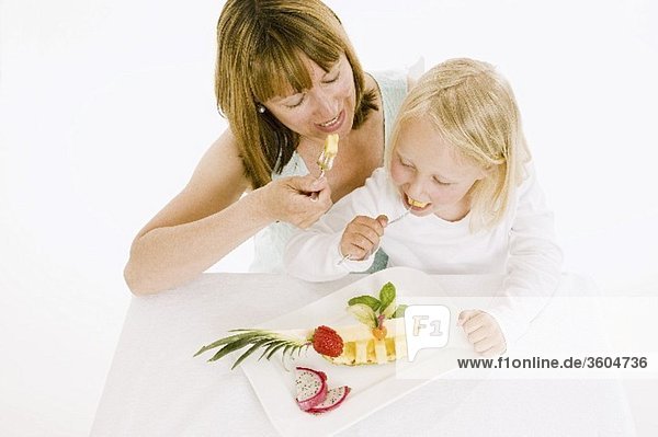 Mutter und Tochter essen Obst vom Obstteller