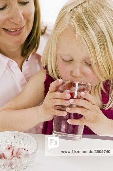Mädchen trinkt Wasser mit Himbeereiswürfeln