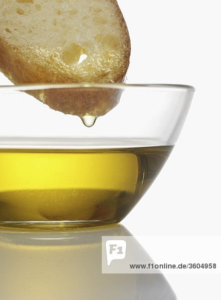 Olivenöl tropft von Brotscheibe