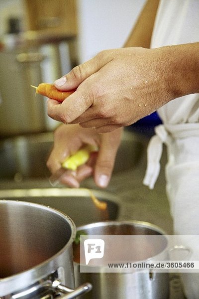Chef in commercial kitchen peeling carrots