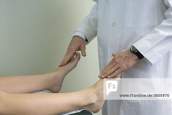 Arzt untersucht die Füße des Patienten