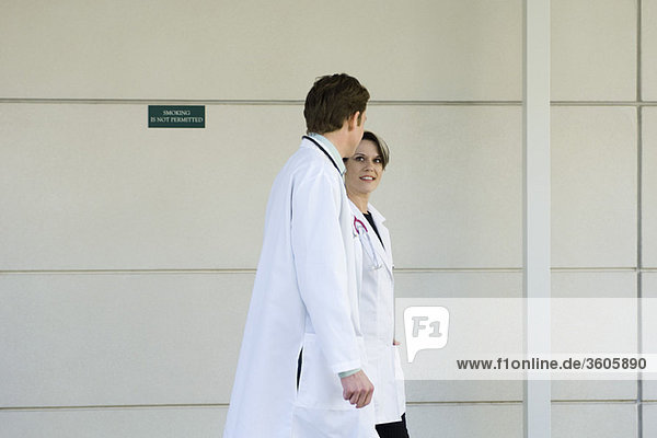 Doctors chatting and walking together along hospital corridor
