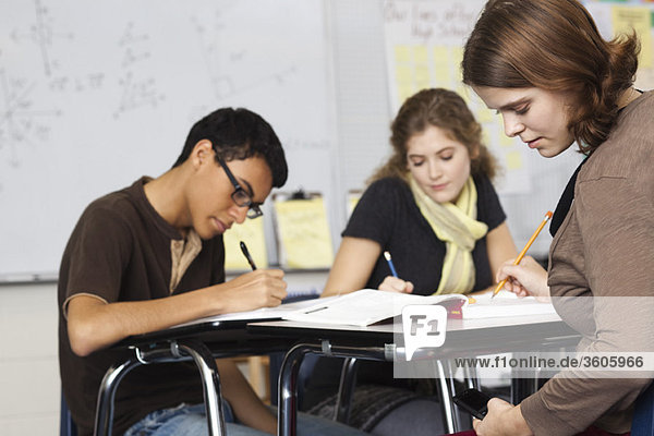 Schüler arbeiten in der Klasse  eine SMS unter ihrem Schreibtisch