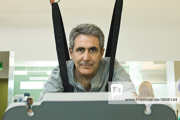 Mann trainiert auf dem Laufband mit Hilfe eines Rehabilitationsgurtes  der das Körpergewicht unterstützt.