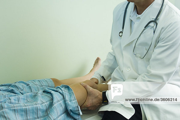 Arzt untersucht das Bein des Patienten