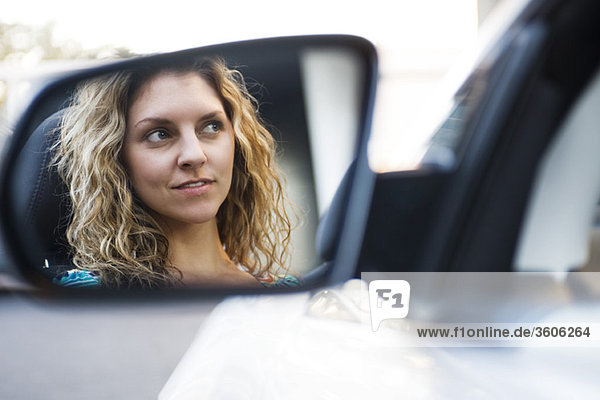 Young woman driving car  reflection in side-view mirror