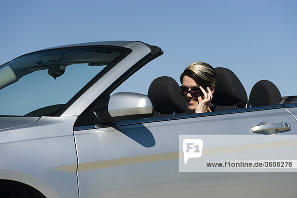 Frau im Cabrio  Sonnenbrille absenken  um in die Kamera zu schauen