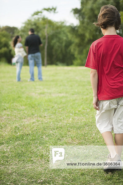 Boy walking sulkily toward parents having conversation distance