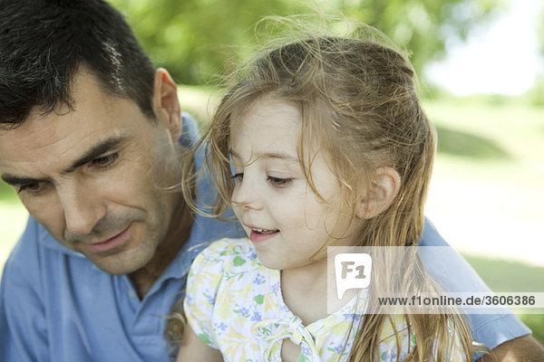 Father and young daughter talking outdoors