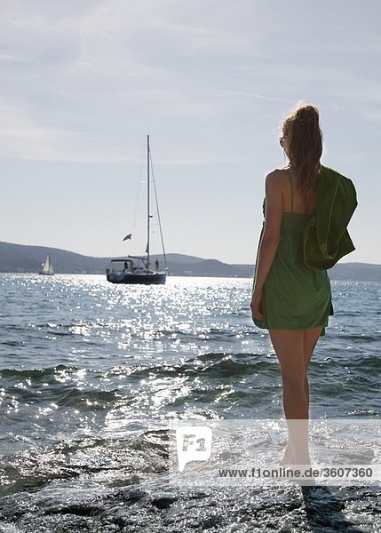 Frau am Strand mit Blick auf die Yacht