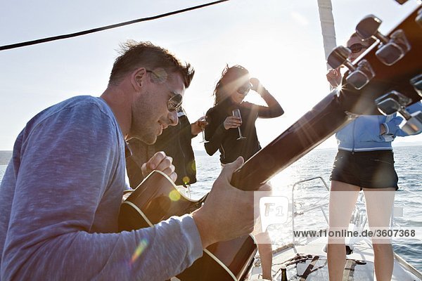 Friends dancing with guitar on yacht