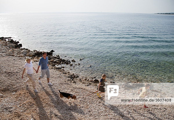 Familie mit Hund beim Laufen am Strand