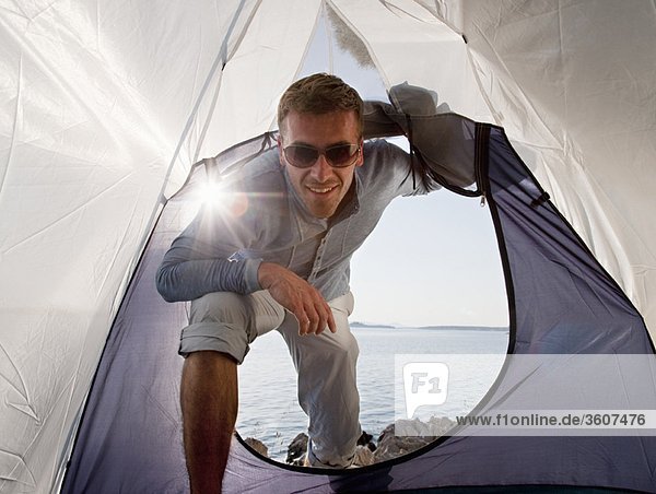 Man entering tent by sea
