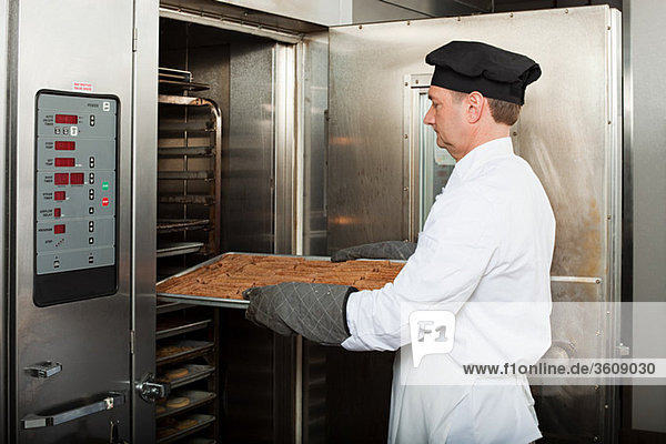 Männlicher Koch backt Kekse in der Großküche
